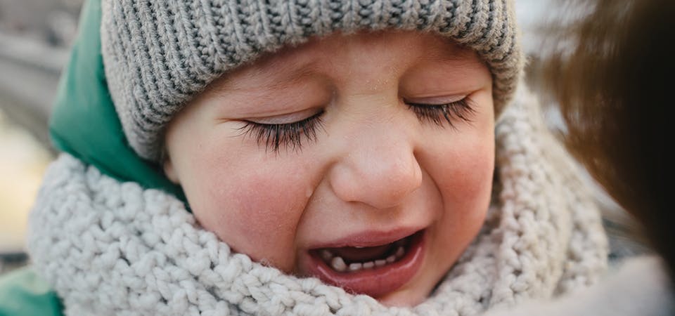 Closeup of young boy in winter clothes hysterical crying, tears streaming down his face.