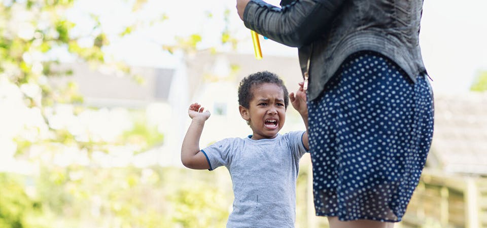 Young toddler boy outside with mom having tantrum not listening, hitting