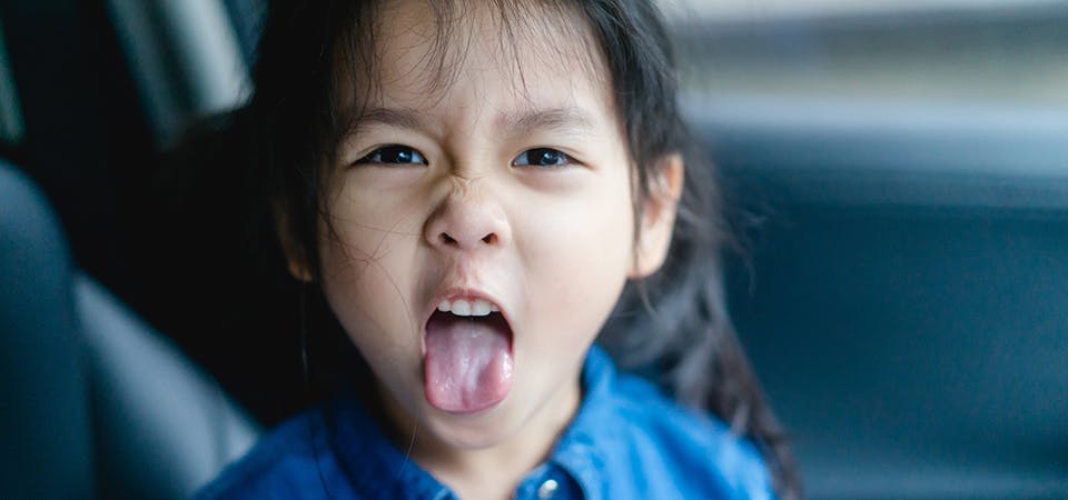 Little girl with pigtails sticking out tongue, making a rude face.