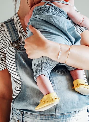 Caucasian mom holding newborn baby on shoulder with left arm
