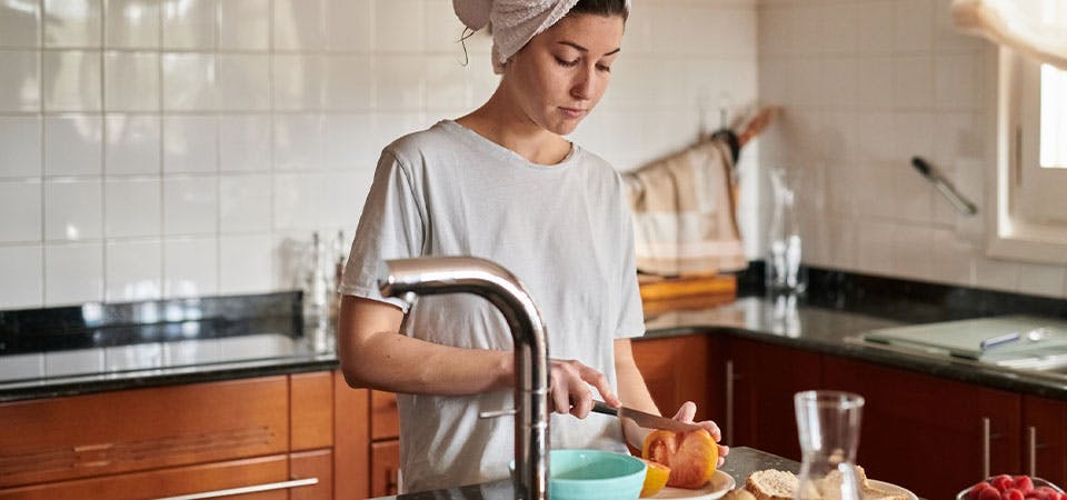 mother in kitchen with towel in hair, preparing breakfast for herself
