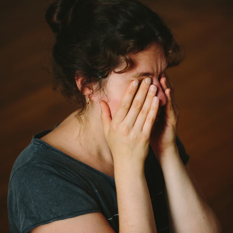 woman in a green shirt rubbing her eyes out of frustration