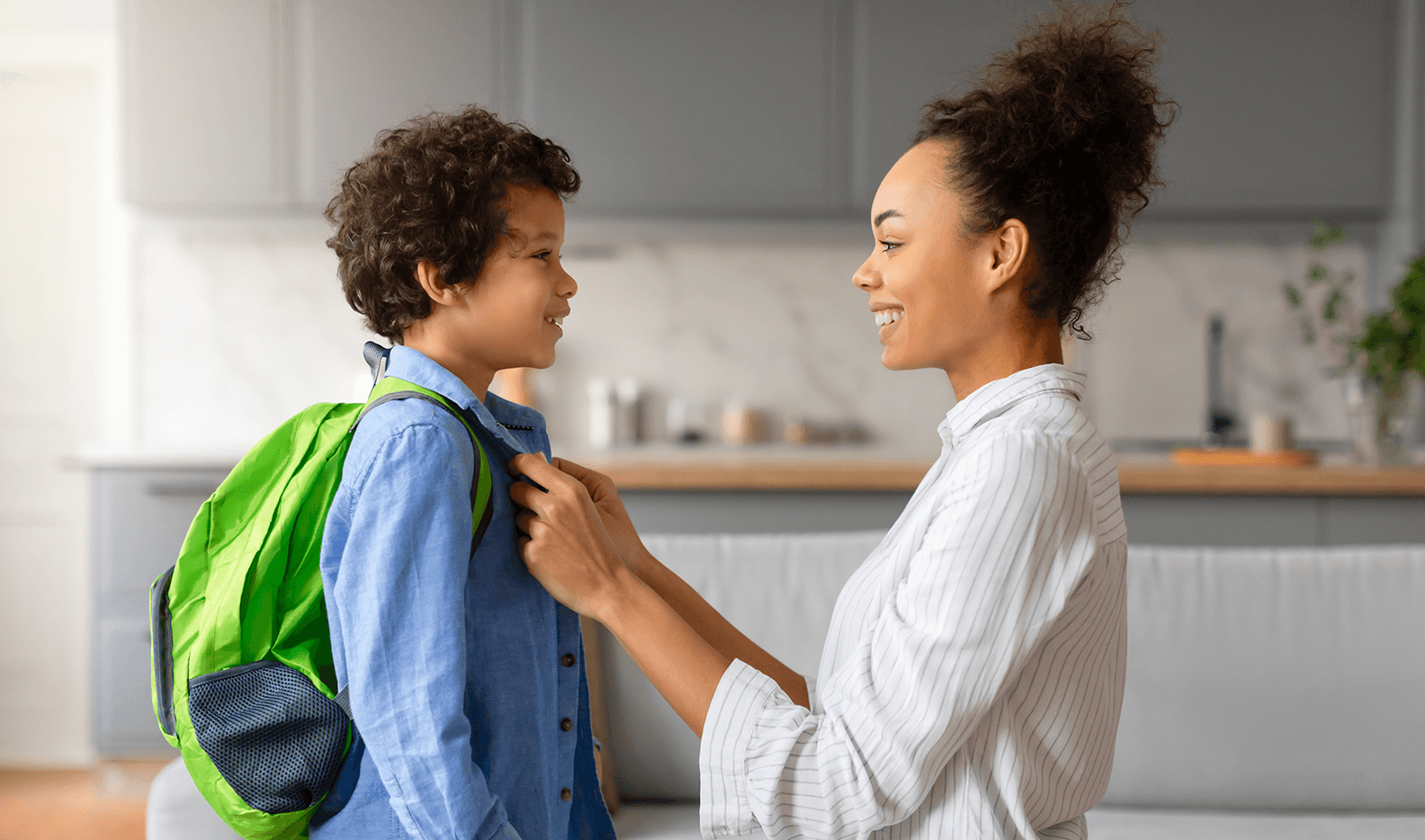 A parent helping their kid with a backpack before school